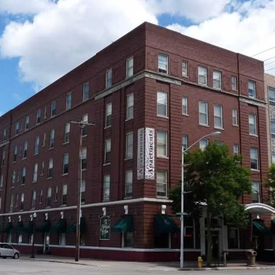 Hereford & Hops Delta Apartments: a four-story red brick building with green awnings on the corner.