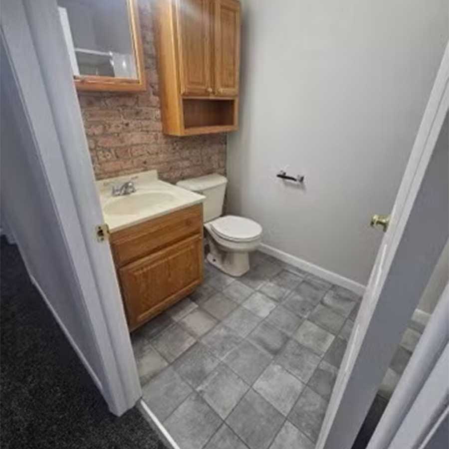 Small bathroom at Hereford & Hops Delta Apartments with sink, toilet, and exposed brick accents.